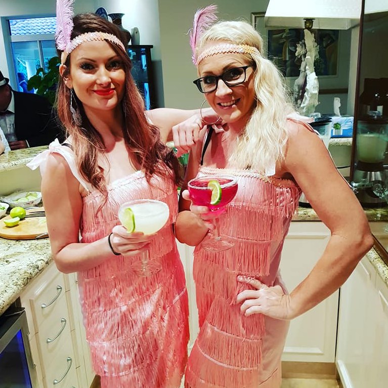Pretty smiling waitresses dressed in Gatsby flapper outfits with cocktails