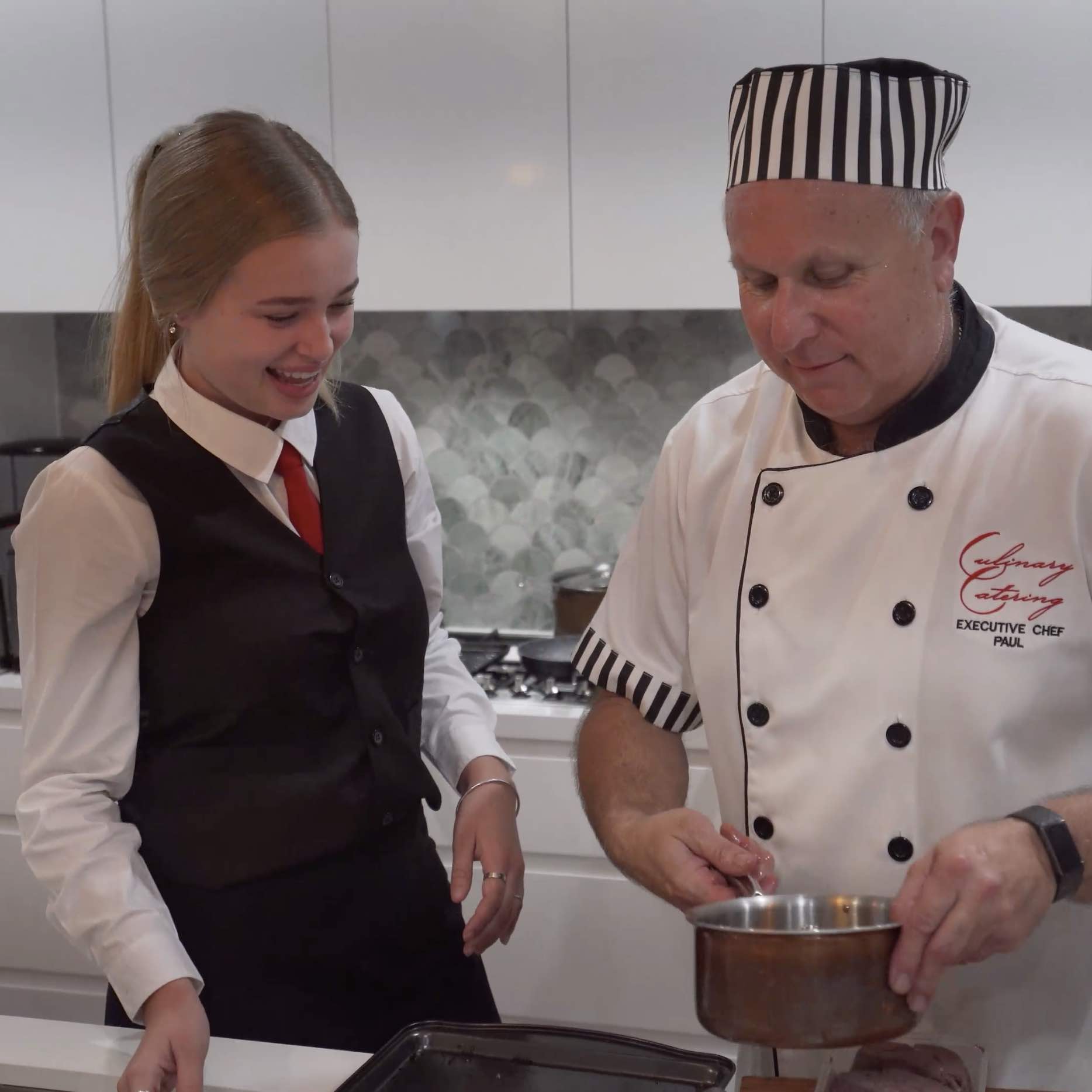 Chef and smiling waitress learning things in the kitchen