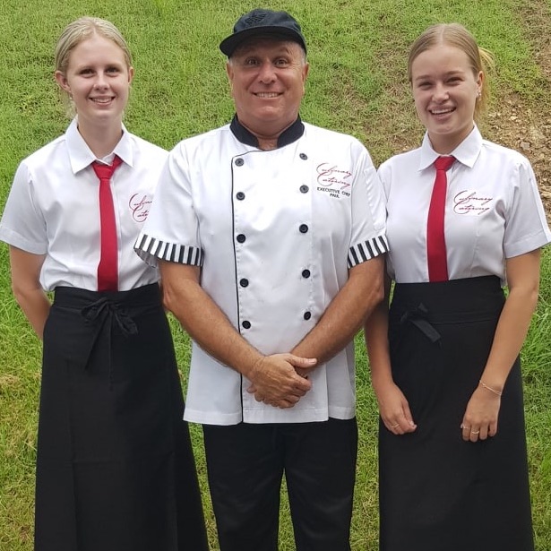 Smiling chef and two blonde waitresses in their new white, black and red uniforms