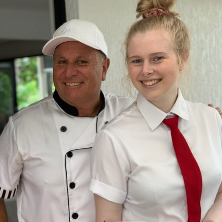 smiling chef and waitress both dressed in fresh white uniforms